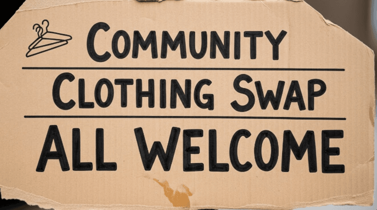 Handwritten sign on cardboard reading Community Clothing Swap All Welcome